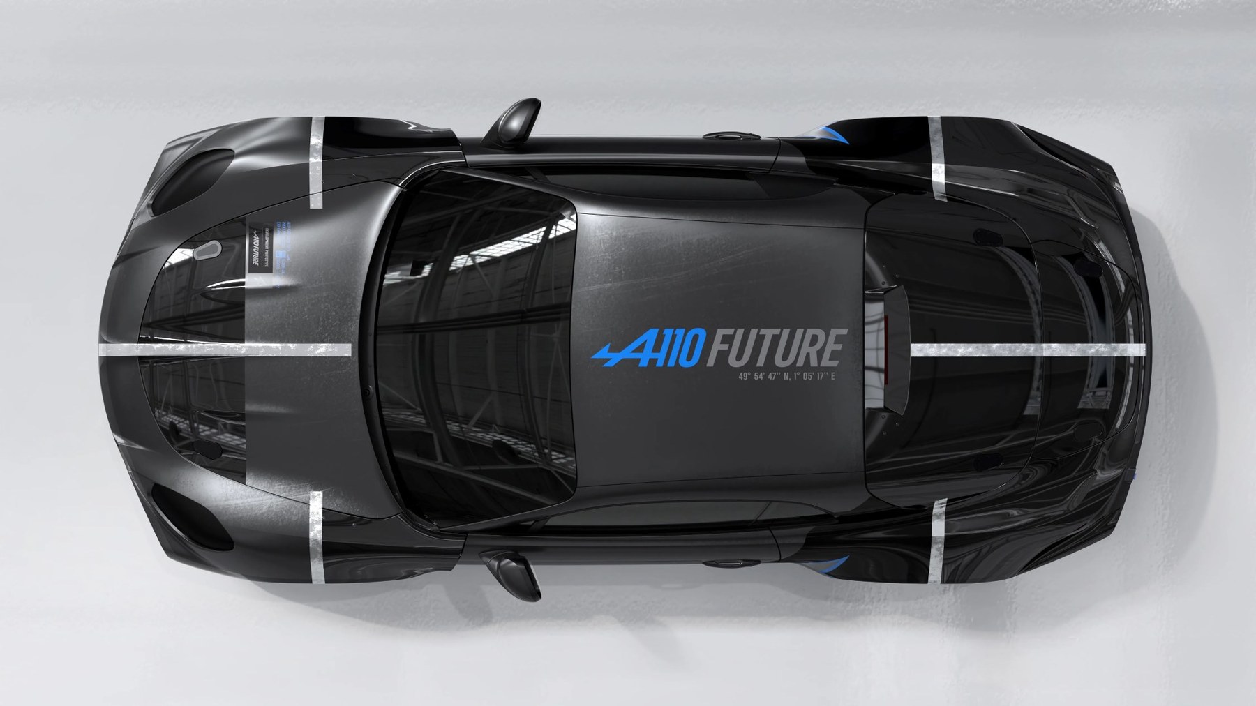 Top view of a black sports car with "A110 FUTURE" text in blue and gray on the roof and white racing stripes.